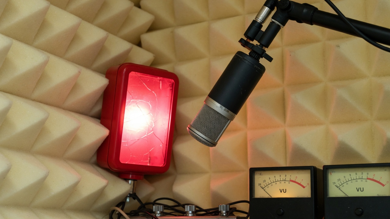 Boom microphone hanging over cream acoustic foam in the booth